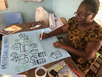 Harieth from Pangani Primary prepares a poster showing various settlement types